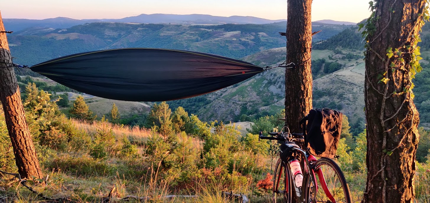 Un vélo avec une sacoche et un hamac dans une vallée